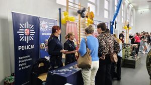 Policjanci na stoisku promocyjnym w szkole.