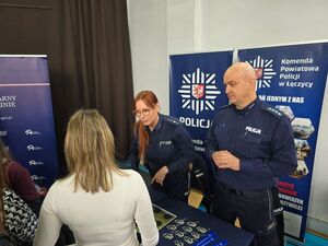 Policjanci na stoisku promocyjnym w szkole.