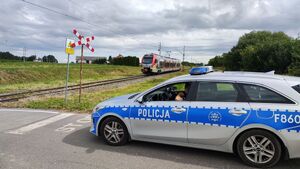 Policjantka i przedstawicielka kolei na przejazdach kolejowych, w tle radiowóz.