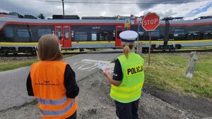 Policjantka i przedstawicielka kolei na przejazdach kolejowych, w tle radiowóz.