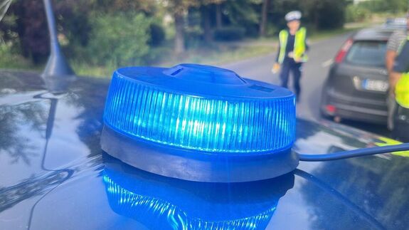 Sygnał świetlny na dachu radiowozu, w tle policjanci.