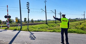 radiowóz i policjant przed przejazdem kolejowym.