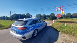 radiowóz i policjant przed przejazdem kolejowym.