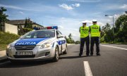 Dwóch policjantów na drodze obok radiowozu.