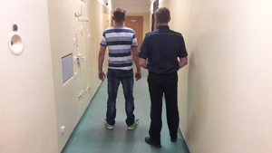 Policjant z zatrzymanym na korytarzu.