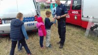 Policjanci obok radiowozu z uczestnikami wydarzenia.