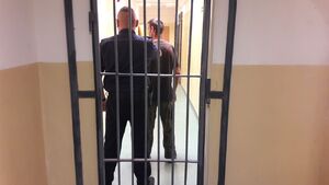 Policjant z zatrzymanym za kratą.