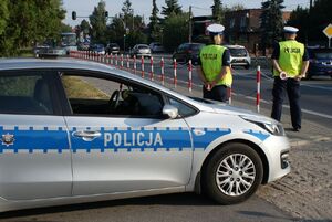 Policjanci obok radiowozu.