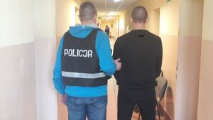 Policjant stoi tyłem z zatrzymanym.