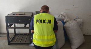 policjant prowadzi oględziny zabezpieczonego tytoniu.